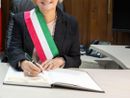 Donna sindaco con fascia tricolore che firma documenti