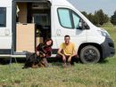 Due persone e un cane davanti a un camper