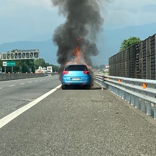 Automobile che brucia ai lati di una strada