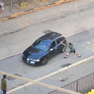 Un ragazzo spacca uno specchietto a un'auto usando un machete