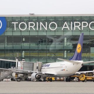 Aeroporto con scritta Torino Airport e un aereo in prima fila