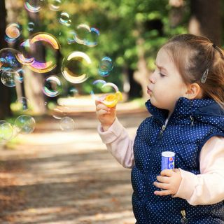 bambina che soffia nelle bolle di sapone