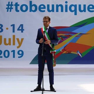 uomo con fascia tricolore che parla al microfono