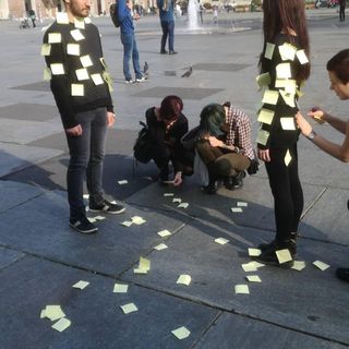 Due ragazzi ricoperti da post it in mezzo a piazza Castello