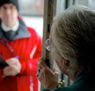 donna anziana apre la porta a uno sconosciuto vestito di rosso