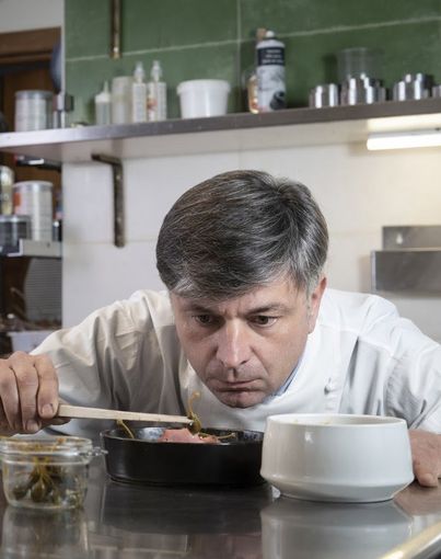Cuoco che assaggia da una pentola con un cucchiaio di legno