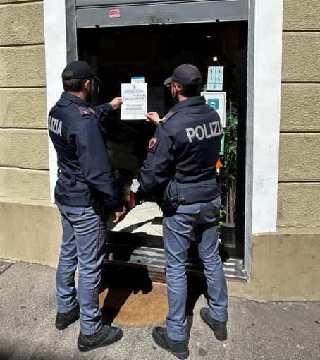 Poliziotti davanti a una saracinesca chiusa Poliziotti davanti a una saracinesca chiusa