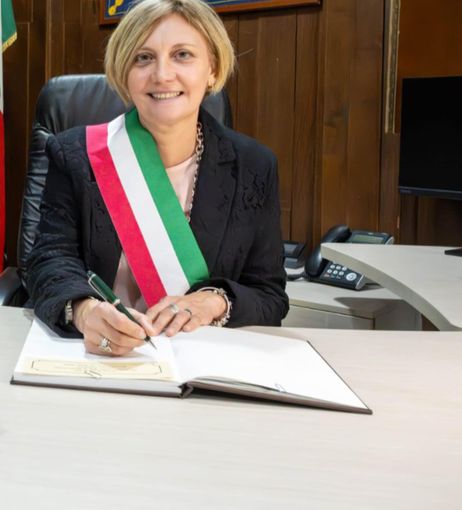 Donna sindaco con fascia tricolore che firma documenti Donna sindaco con fascia tricolore che firma documenti