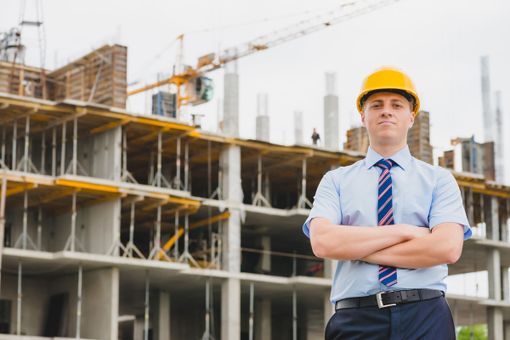 persona con caschetto davanti a un cantiere edile