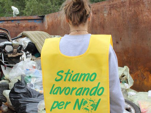 Un volontario di Puliamo il mondo di spalle, con pettorina gialla