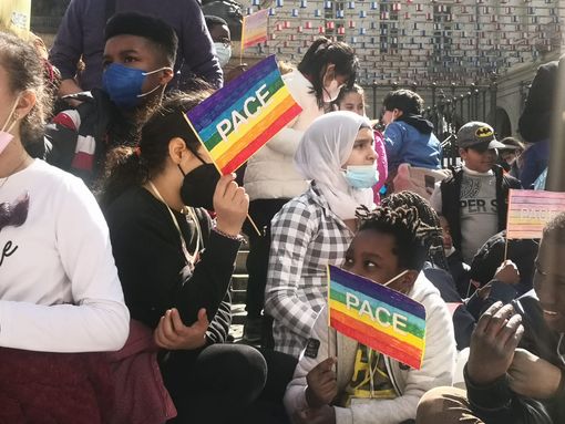 ragazzi e manifestanti che chiedono pace con bandiere arcobaleno