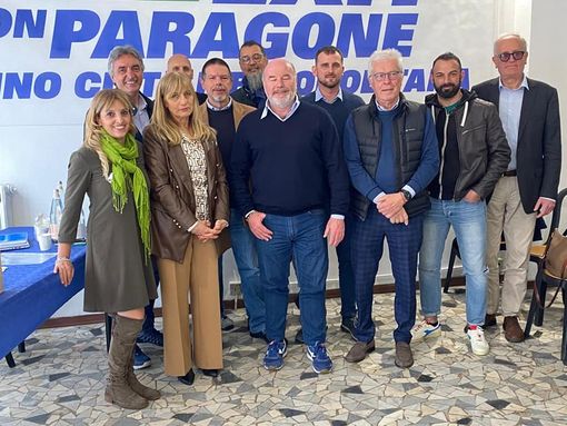 foto di gruppo davanti a simbolo di partito