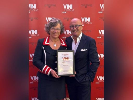 due persone in piedi con un premio in mano due persone in piedi con un premio in mano