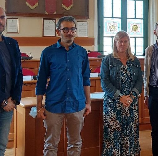 Quattro persone in piedi nella sala del consiglio comunale di Venaria