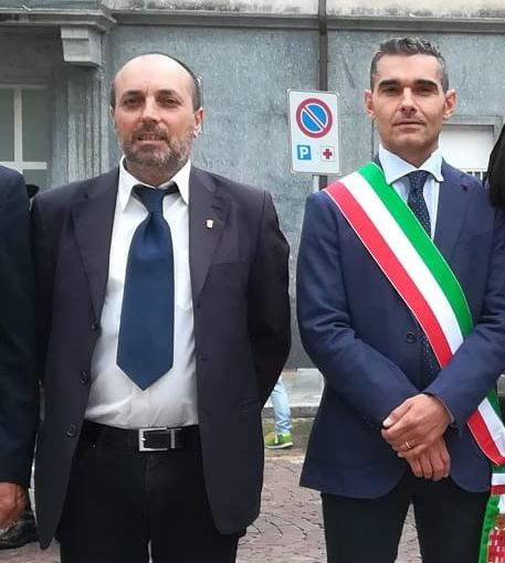 Due persone in piedi, una con fascia tricolore