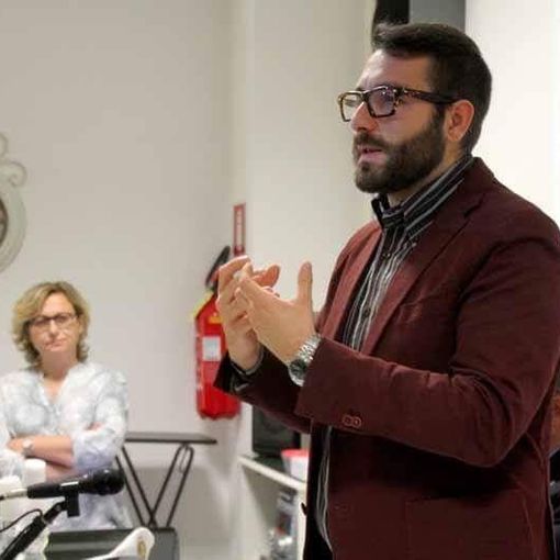 uomo con occhiali che parla in pubblico