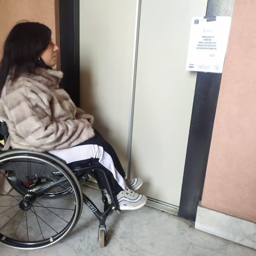 Maria Naum sulla sua carrozzina davanti all'ascensore guasto