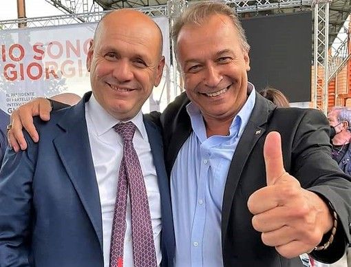 Due persone in primo piano, uno fa il segno ok con il la mano
