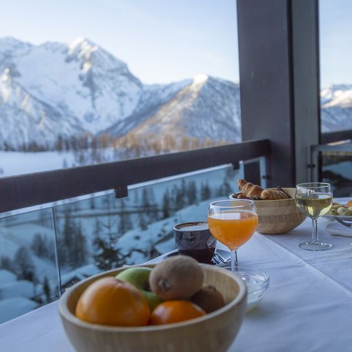 Vista sulla montagna innevata dal Bravo Club di Sestriere, con un tavolo apparecchiato in primo piano