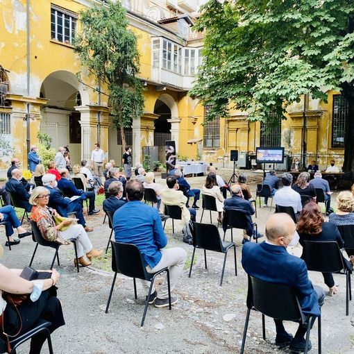 Persone sedute su sedie distanziate in un cortile