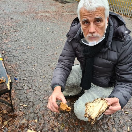 Uomo seduto vicino a una panchina danneggiata