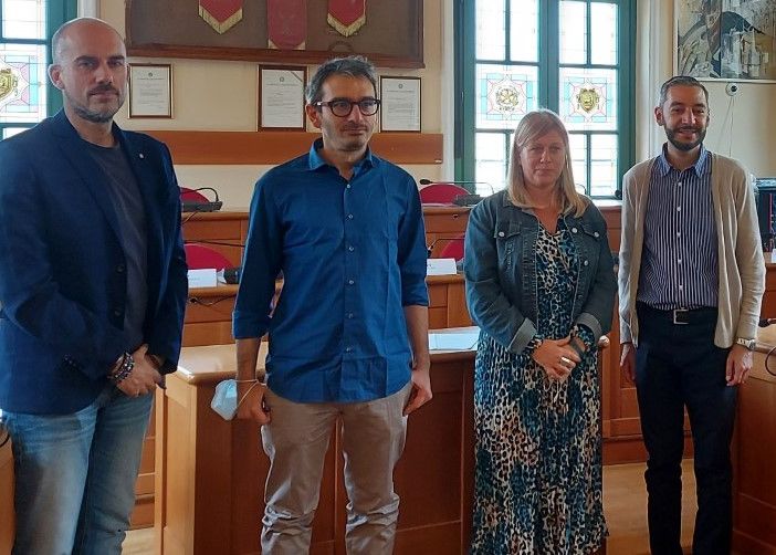 Quattro persone in piedi nella sala del consiglio comunale di Venaria