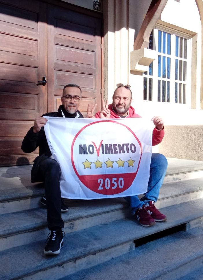 Due persone sedute sui gradini con bandiera 5 stelle