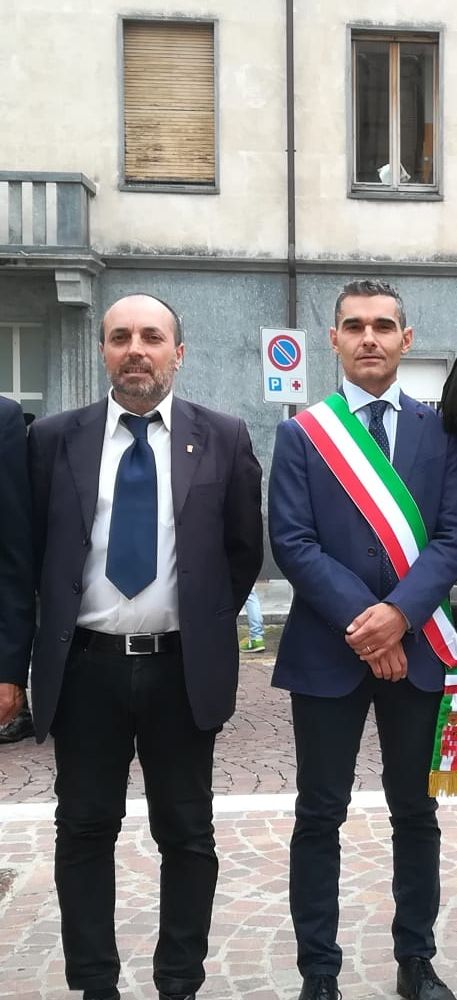 Due persone in piedi, una con fascia tricolore