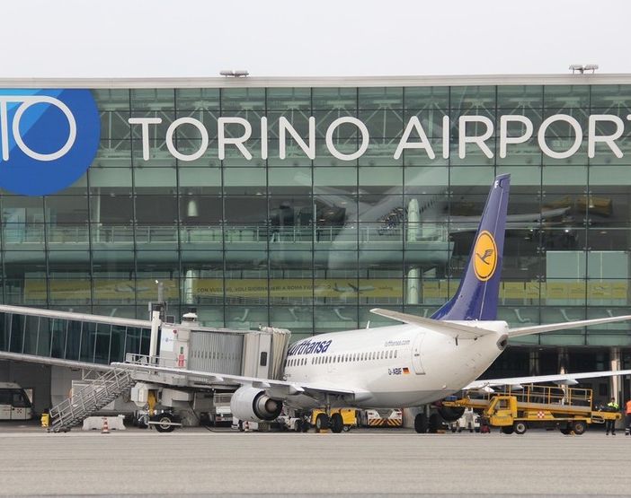 Aeroporto con scritta Torino Airport e un aereo in prima fila