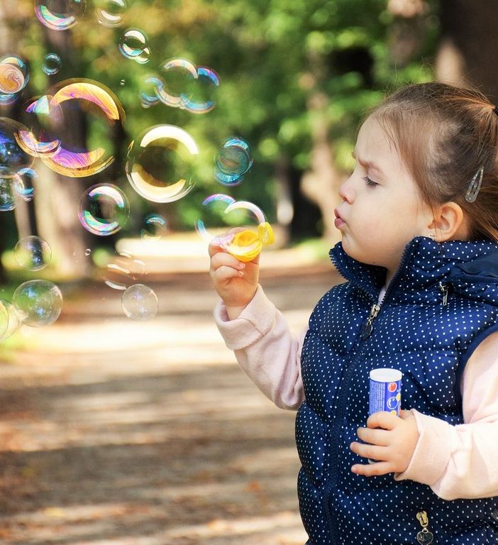 bambina che soffia nelle bolle di sapone