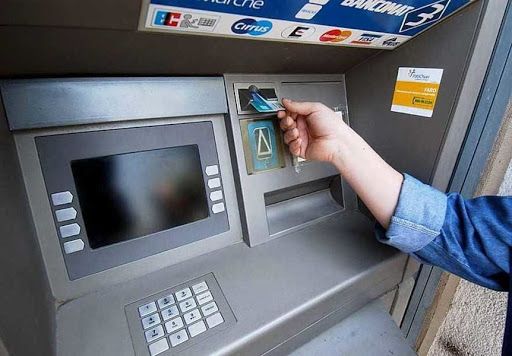 sportello bancomat con persona che fa il prelievo