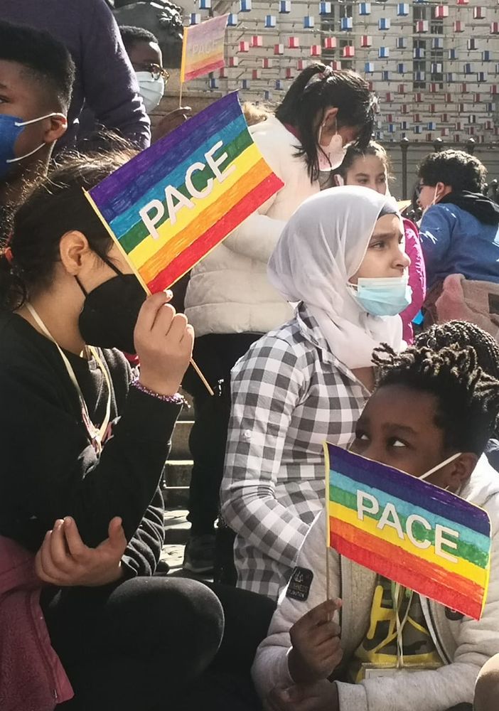 ragazzi e manifestanti che chiedono pace con bandiere arcobaleno