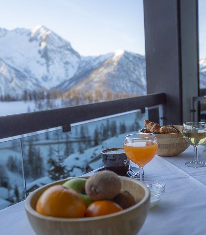 Vista sulla montagna innevata dal Bravo Club di Sestriere, con un tavolo apparecchiato in primo piano