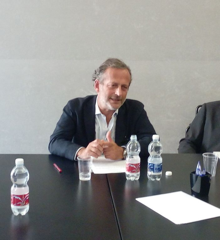 Alessandro Cherio seduto a un tavolo mentre parla