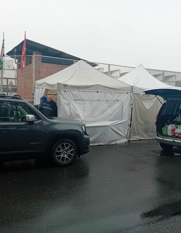 Persone insieme tra due auto con bagagliaio aperto