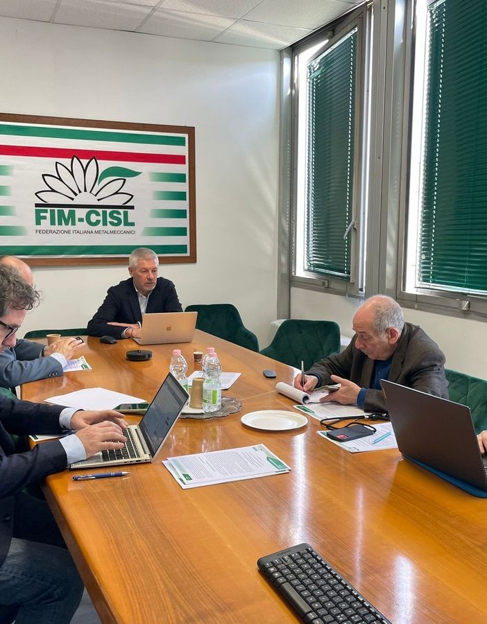 tavolo con persone e bandiera Fim Cisl