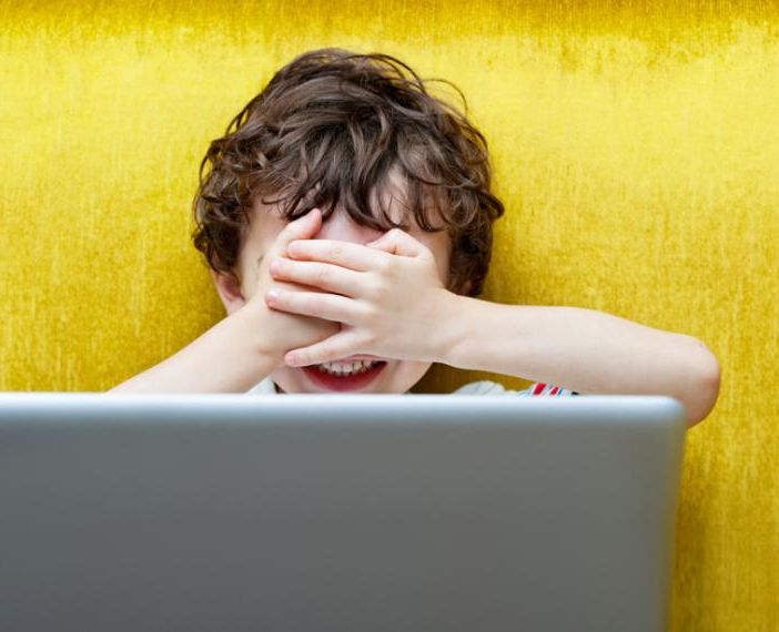 Bambino che si copre il volto davanti a un computer