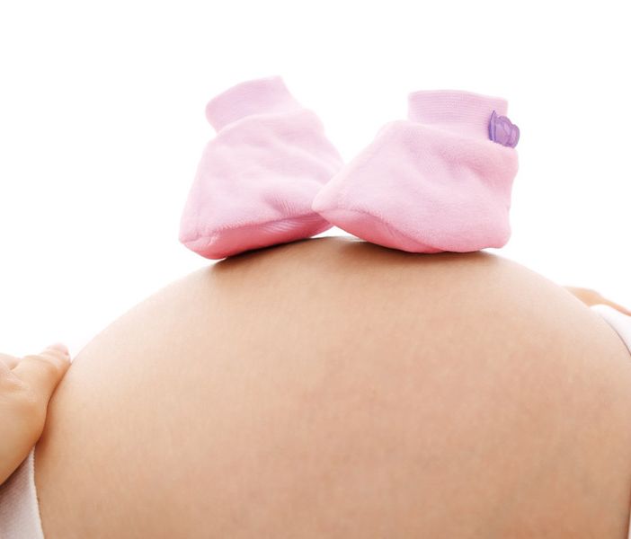 Donna incinta con scarpine bimba sulla pancia