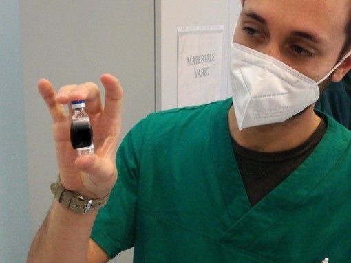 Un vaccino anticovid in siringa con mano e guanto