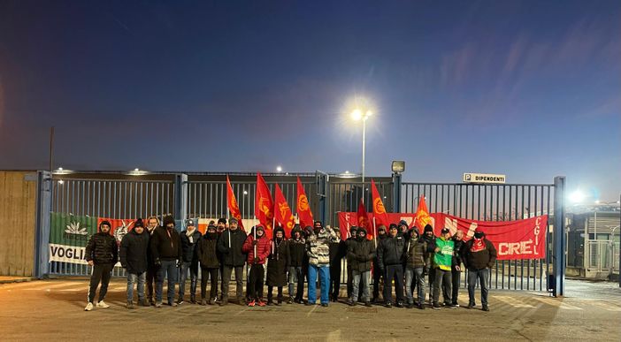 operai con bandiere davanti ai cancelli dell'azienda