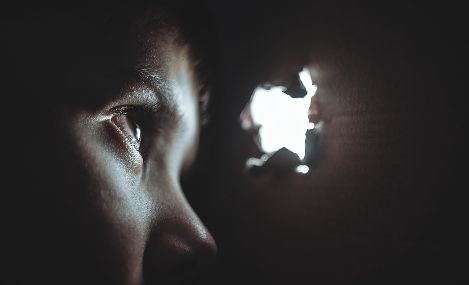 bimbo che guarda da un buco nel muro