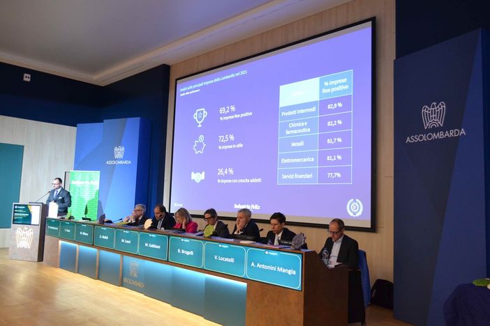 convegno in una sala con palco rialzato e schermi illuminati