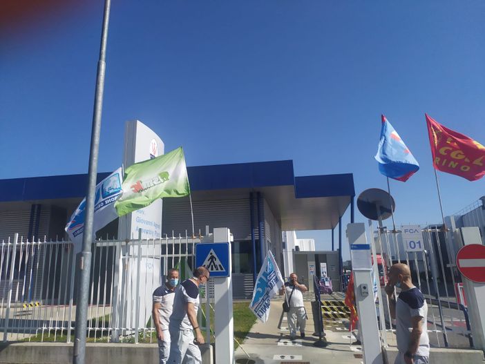 sindacalisti che montano bandiere su un cancello di azienda