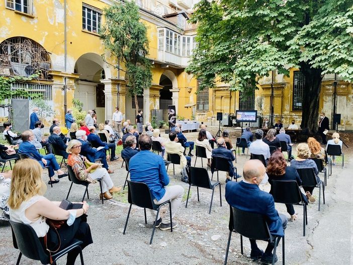 Persone sedute su sedie distanziate in un cortile Persone sedute su sedie distanziate in un cortile