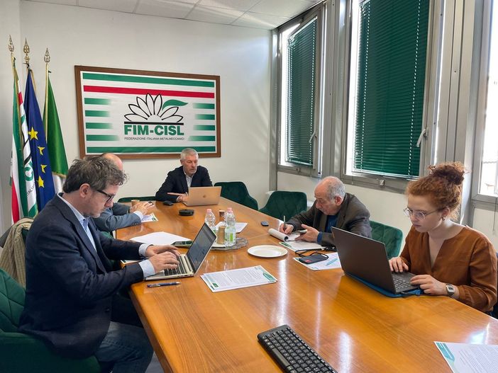 tavolo con persone e bandiera Fim Cisl tavolo con persone e bandiera Fim Cisl