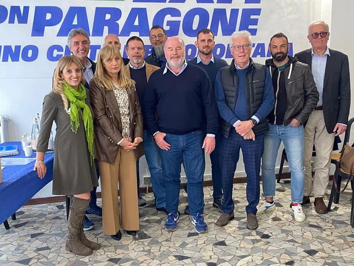 foto di gruppo davanti a simbolo di partito