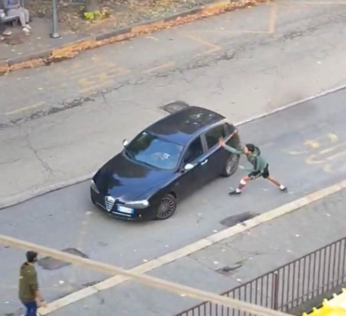 Un ragazzo spacca uno specchietto a un'auto usando un machete