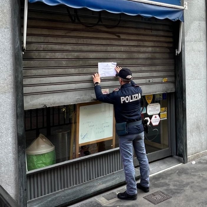 Poliziotto che affigge un cartello di chiusura Poliziotto che affigge un cartello di chiusura