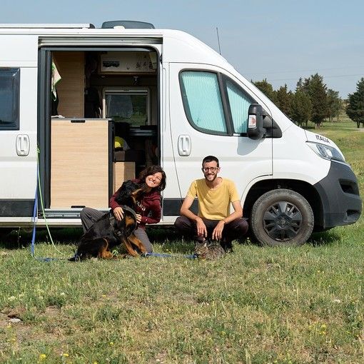 Due persone e un cane davanti a un camper