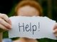 Ragazza tiene in mano cartello con la scritta &quot;help&quot;